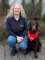 Vergrößerte Ansicht von Eine Frau kniet neben einem Hund. Auf seinem roten Halstuch steht "Malteser" und "Amber".