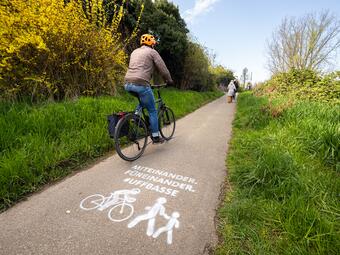 Vergrößerte Ansicht von Fahrrad fährt auf Radweg. Kreidespray auf Fahrbahn weist auf ein rücksichtsvolles Miteinander hin