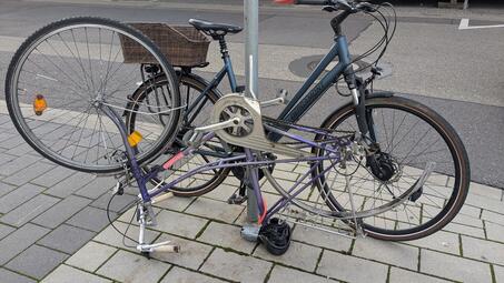 Vergrößerte Ansicht von Dieses Schrottfahrrad ohne Hinterrad versperrt einen Teil des Gehwegs.