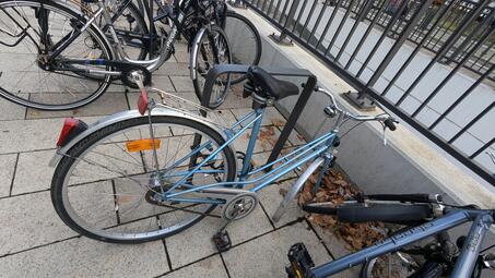 Vergrößerte Ansicht von Dieses Schrottfahrrad ohne Vorderrad belegt einen Fahrradbügel am Hauptbahnhof.