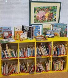 Vergrößerte Ansicht von Ein gelbes Regal mit vielen Bilderbüchern.
