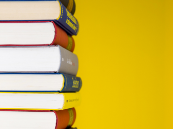 Vergrößerte Ansicht von Ein Stapel Bücher vor gelbem Hintergrund.