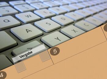 Tastatur mit Aktenordner Aufschrift Vergabe