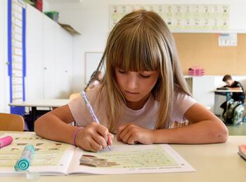 Grundschülerin schreibt in Heft
