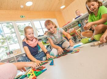 Grundschulkinder bauen mit Bausteinen sitzend auf dem Boden