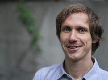 Tobias Steinfeld lächelt in die Kamera und trägt ein blaues Hemd.